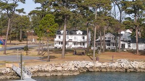 A lakeside property with multiple houses, a dock, and a picnic area. - Channel Lookout | Memorial Park Water Views w/ Private Deck, Assateague Channel Scenery & Fishing (Chincoteague Island)