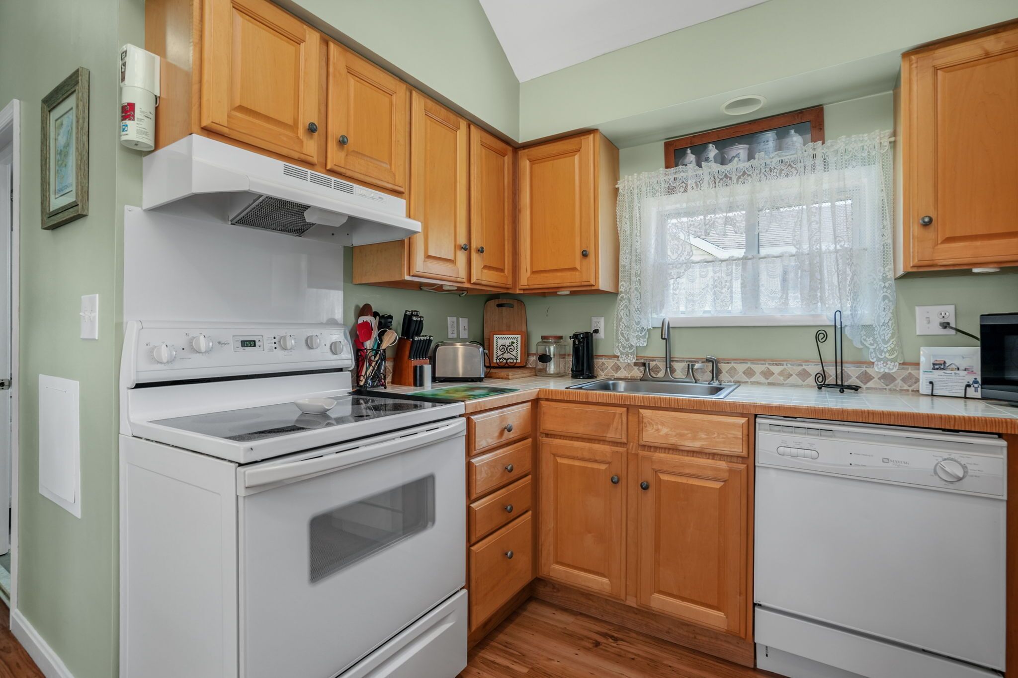A kitchen with wooden cabinets, a white stove, and a dishwasher.