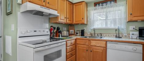 A kitchen with wooden cabinets, a white stove, and a dishwasher.