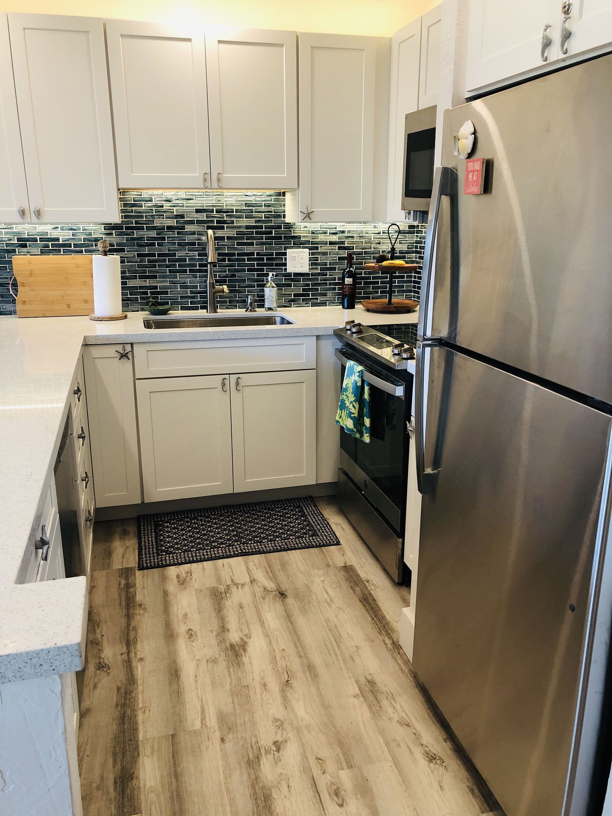A modern kitchen with light-colored cabinets, a stainless steel refrigerator, a microwave, and a wooden countertop.