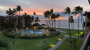 Et resort med poolområde, palmer og havudsigt i solnedgang.