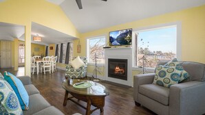 Un salon avec une cheminée, un ventilateur de plafond et un téléviseur.