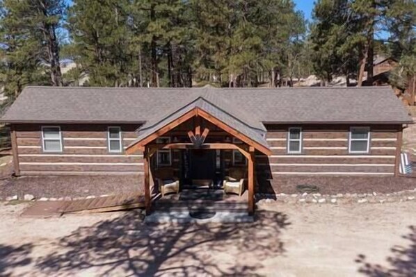 A log cabin with a central porch and two windows on the side.