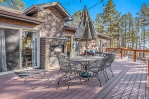 A patio with a stone fireplace, outdoor furniture, and a view of trees. - Black Forest Retreat (Colorado Springs)