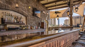 A bar with a wooden counter, bottles, and a city view through large windows. - 1BD/Orlando - Near Disney - Private Kitchen and Living Area! (Lake Buena Vista)