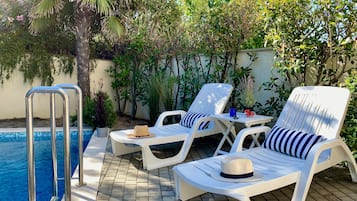 Una piscina al aire libre, tumbonas