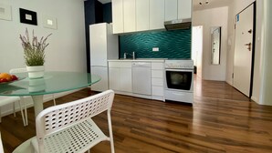 Una cocina moderna con armarios blancos, salpicadero verde azulado y horno empotrado.