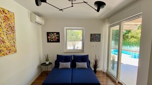 Un dormitorio moderno con una cama grande, una lámpara en el techo, una ventana y vista a una piscina al aire libre.