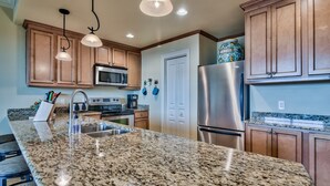 A kitchen with granite countertops, stainless steel appliances, wooden cabinets, and pendant lighting. - 5th floor, Gulf views, 2 Pools, Free Beach Service, Garage Parking (Miramar Beach)
