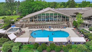 A pool area with a large building in the background, surrounded by greenery. - Sail Away @ Abbey Springs |Golf Cart |Golf Course |Wooded View |Wraparound Deck |Pool |Tennis |Beach (Fontana)