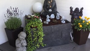 Un espace dédié à la méditation, agrémenté d’une statue de Bouddha, d’une statue de Bouddha rieur et de diverses plantes.