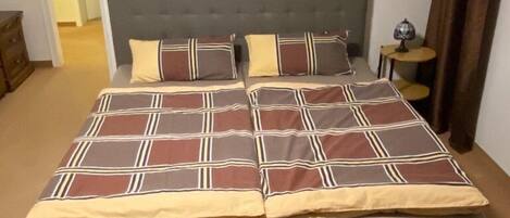 A bedroom with a large bed, two wall-mounted decorative items, a nightstand, and a lamp.