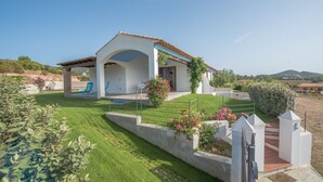 Una casa moderna con patio coperto, prato curato e vista sul paesaggio circostante.