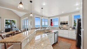 A spacious kitchen with granite countertops, white cabinetry, and stainless steel appliances.