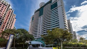 Un hotel grattacielo con facciata curva, numerosi balconi e un ingresso centrale.