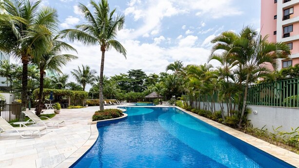 Una piscina con palme e lettini.