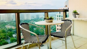 Un balcone con due sedie e un tavolino, vista sulla città.