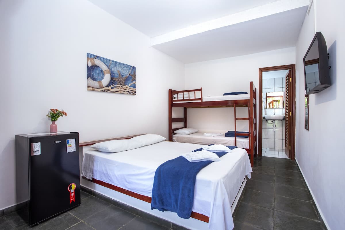 A bedroom with a bunk bed, a single bed, a refrigerator, a painting, and a TV.