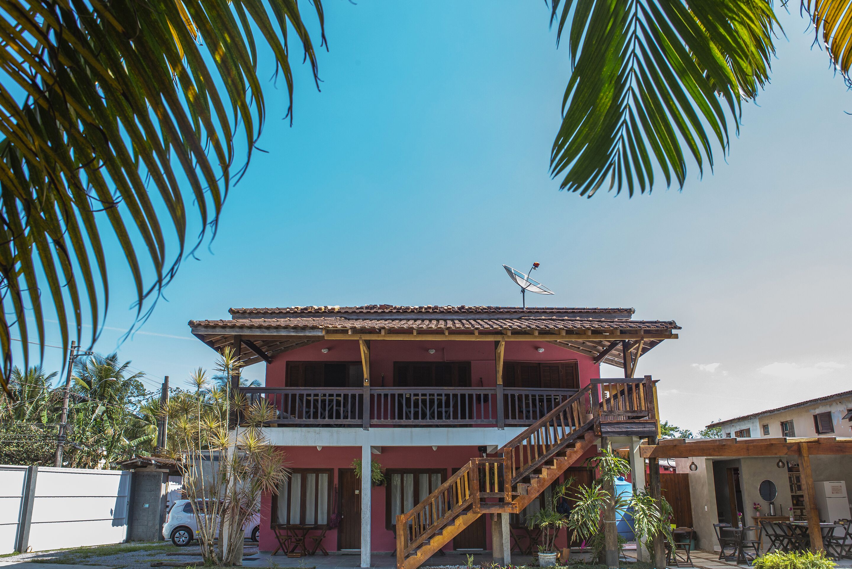 A two-story building with a balcony, a staircase, and a satellite dish.