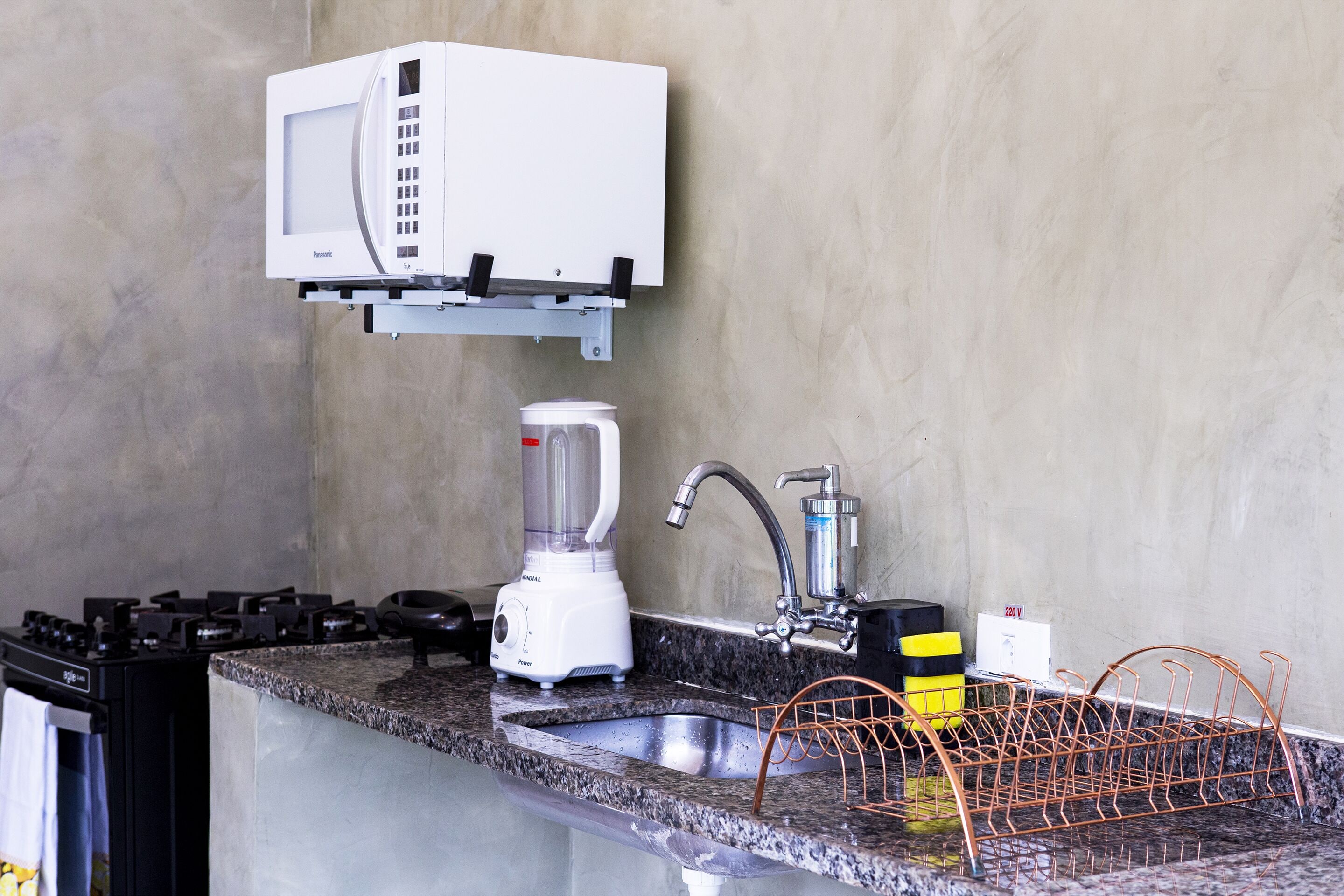 Una cucina attrezzata con forno a microonde, frullatore, lavello e scolapiatti.