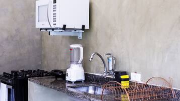 Una cucina attrezzata con forno a microonde, frullatore, lavello e scolapiatti.