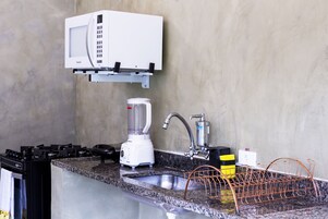 Una cucina attrezzata con forno a microonde, frullatore, lavello e scolapiatti.