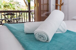 A neatly made bed with a teal towel and a white towel on a white mattress.