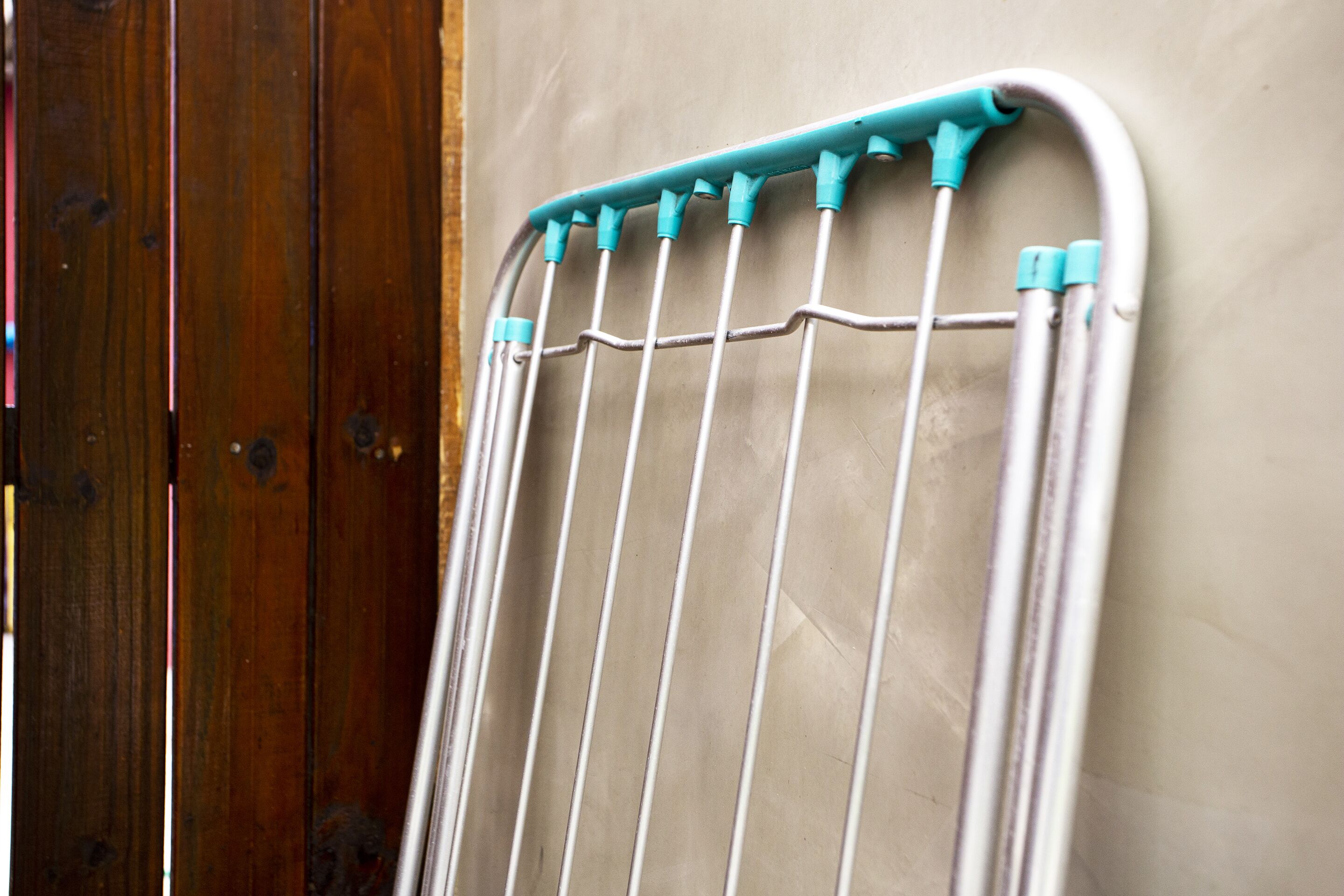 A metal drying rack with multiple pegs against a wall.