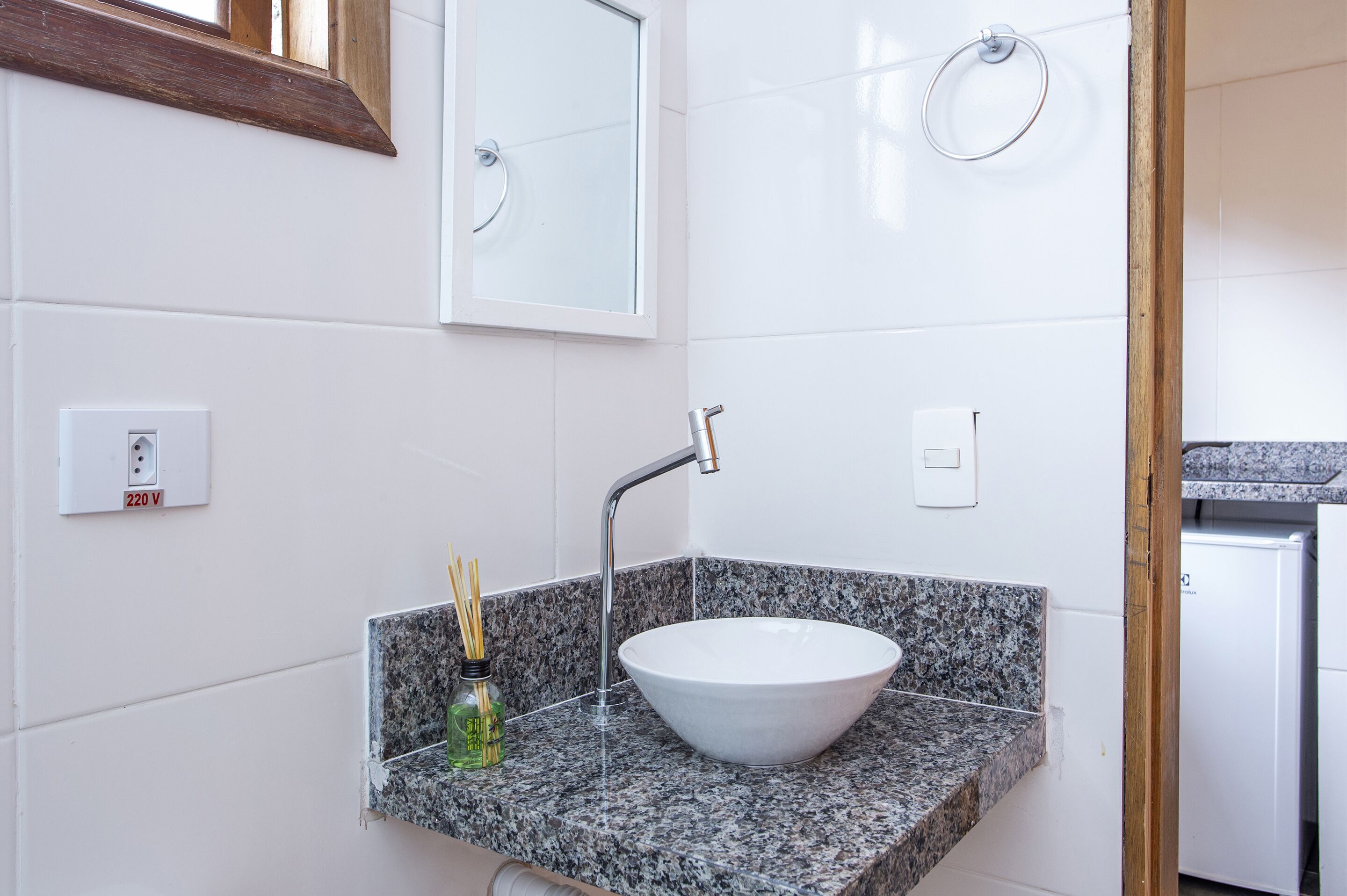 A bathroom with a white sink, granite countertop, and a mirror above it.