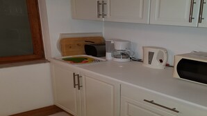A kitchen with white cabinets, a toaster, a coffee maker, and a microwave. - Hansa Apartments Hamburg - Apartment 1B (Wandsbek)