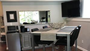 A modern kitchen with a dining area, featuring a large flat-screen TV, a microwave, and a coffee maker. - Lower Level Entry Home with private Patio & back yard. (Nanaimo)