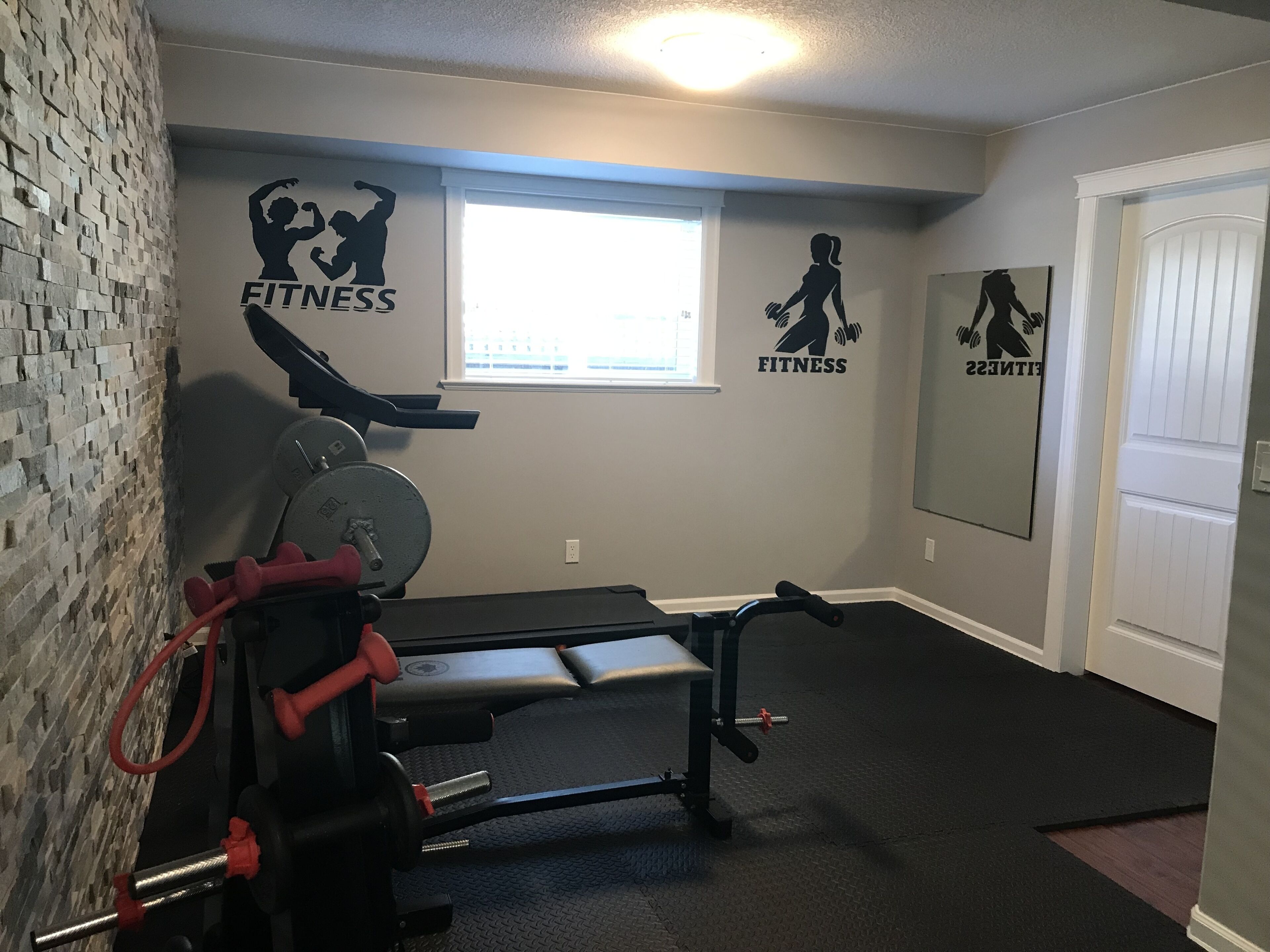 A home gym with exercise equipment, a window, and motivational fitness wall art.