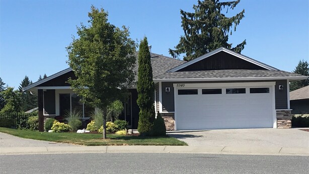 A residential house with a garage, a driveway, and a well-maintained lawn. - Lower Level Entry Home with private Patio & back yard. (Nanaimo)