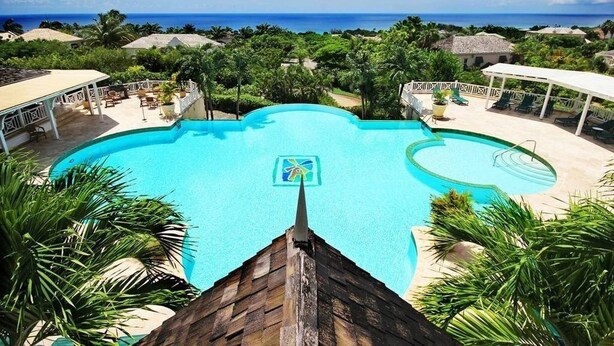 A large, clear swimming pool with a view of the ocean, surrounded by lush greenery and a covered seating area. - Stunning Penthouse with sea views, exclusive estate with Beach Club Membership  (Mount Standfast)