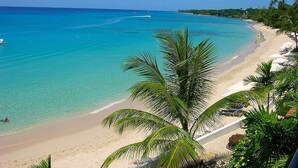 A beach with clear turquoise water, a sandy shore, and palm trees. - Stunning Penthouse with sea views, exclusive estate with Beach Club Membership  (Mount Standfast)