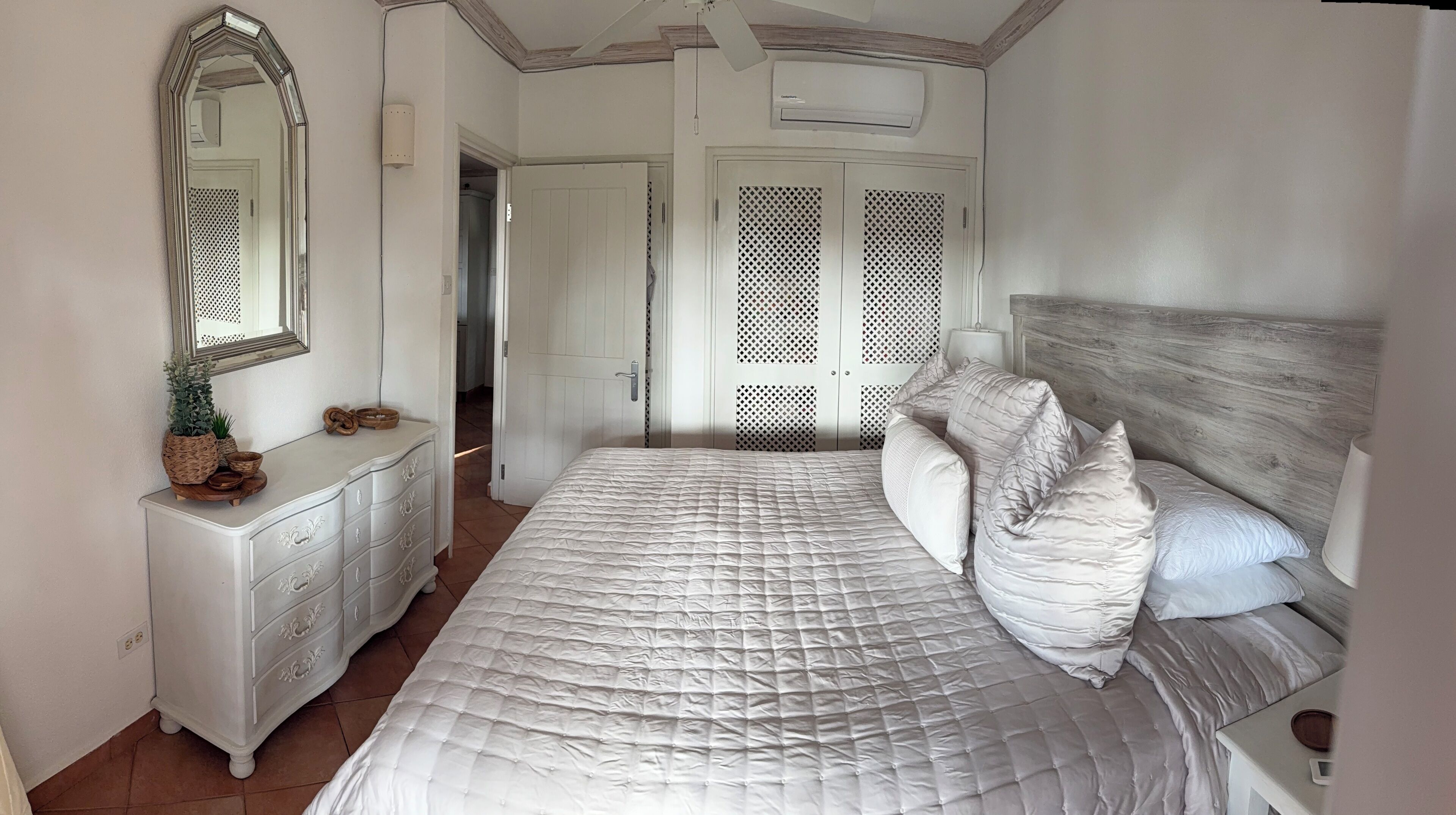 Un dormitorio con una cama grande, un aparador, un espejo y un armario.