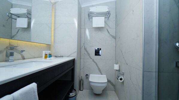Un baño moderno con tocador de mármol, inodoro y zona de ducha.