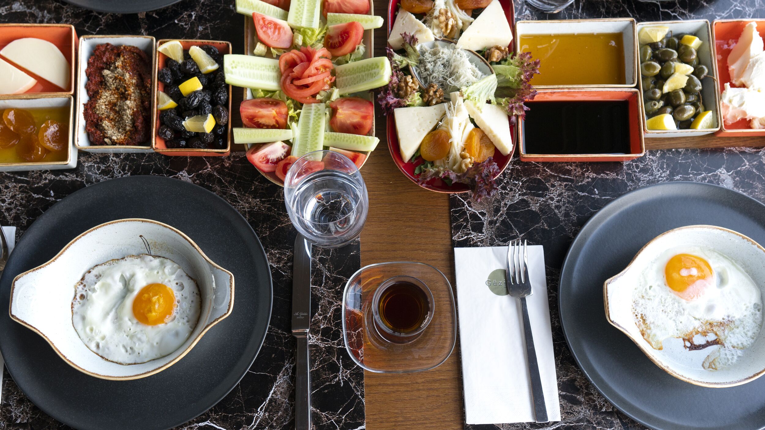 A breakfast setting with eggs, fruits, and cheese on a marble table.