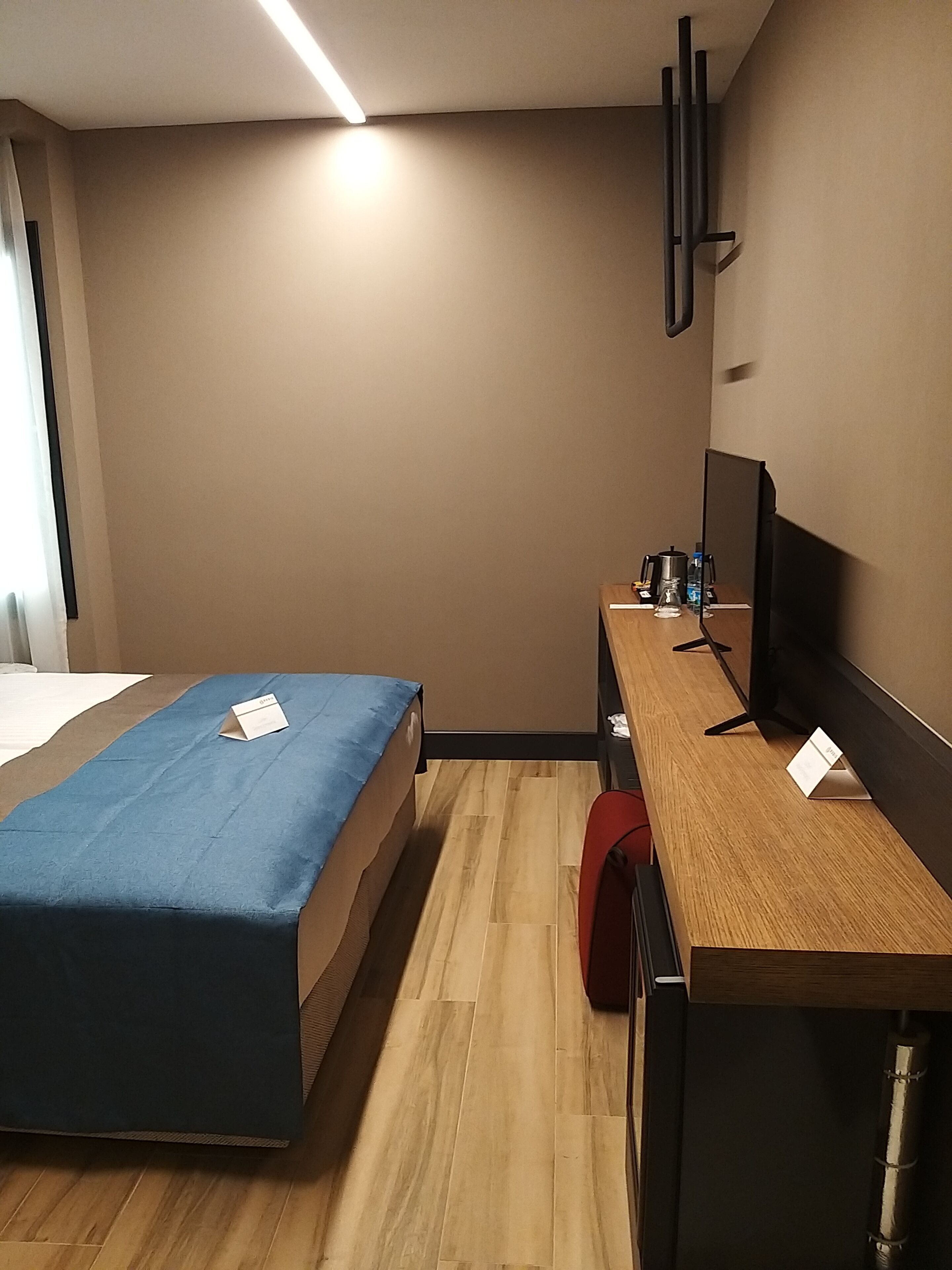 A hotel room with a bed, a desk with a computer, a chair, and a TV.