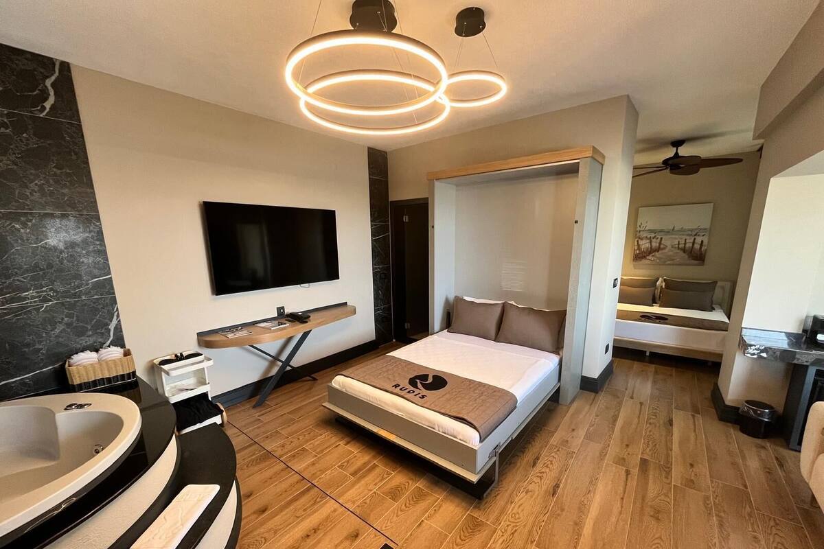A modern hotel room with a large bed, a TV, a desk, and a bathroom with a bathtub.