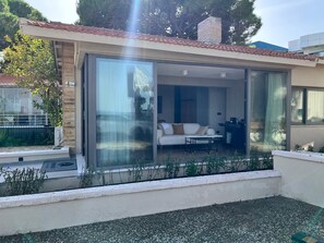 A modern house with a glass-enclosed living area, a white sofa, and a small table.