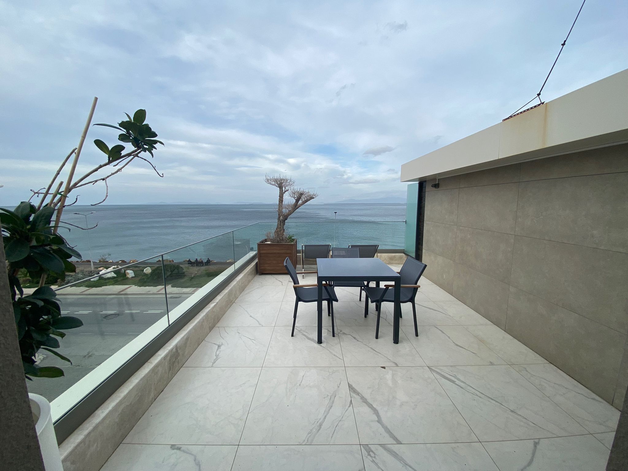A balcony with a table and chairs, overlooking a body of water and distant land.