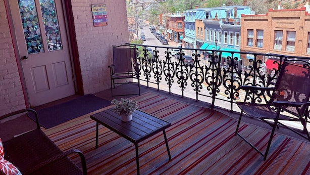 A balcony with a view of a town, a door, and a small table with a plant. - Loft Apartment - Manitou (Manitou Springs)