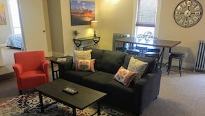 A living room with a sofa, armchair, coffee table, and a dining table with chairs. - Loft Apartment - Manitou (Manitou Springs)