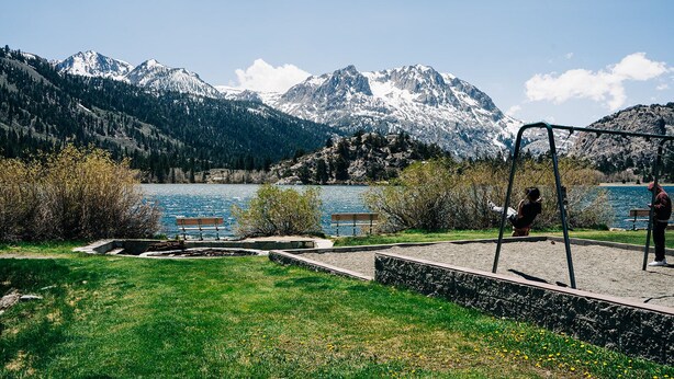 A park with a swing set, benches, and a lake with mountains in the background. - June Lake Home with a view - 2bd / 2ba + loft (June Lake)
