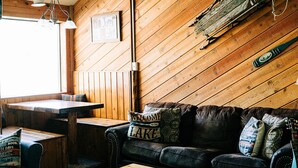 A cozy cabin interior with wooden walls, a leather couch, a wooden coffee table, and a rustic sled. - June Lake Home with a view - 2bd / 2ba + loft (June Lake)