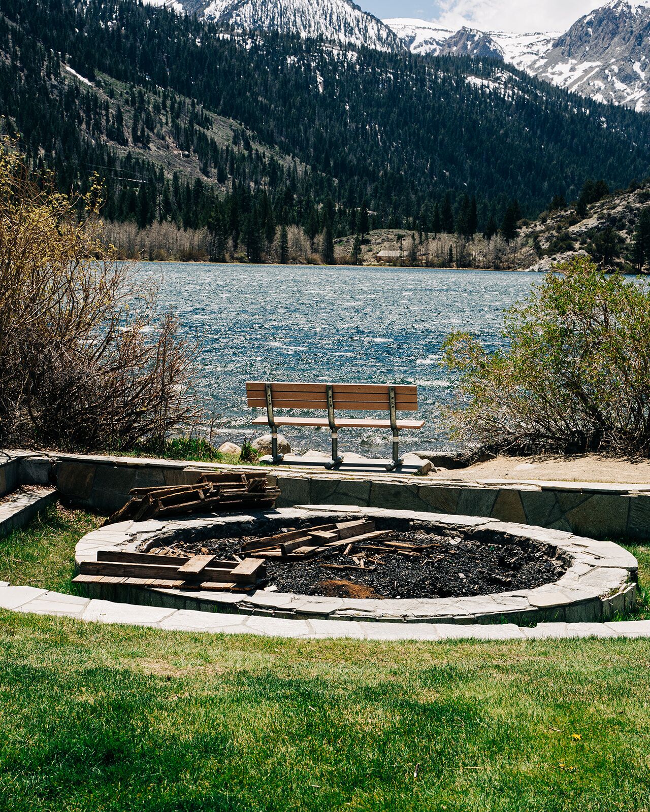 A bench overlooking a lake with mountains in the background.