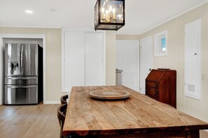 A modern kitchen with stainless steel appliances, a wooden dining table, and a chandelier. - Mid-Century Modern Albert Home (Stonewall)