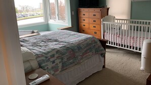 Un dormitorio con cama, cómoda, cuna y televisor.
