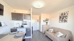 Un espacio habitable compacto con kitchenette, zona de comedor y área de descanso.